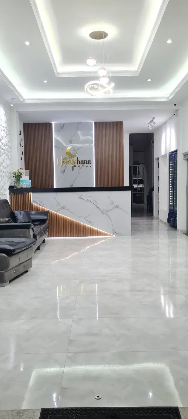 Recepción del Hotel Villa Johana con pisos de mármol y logo dorado
